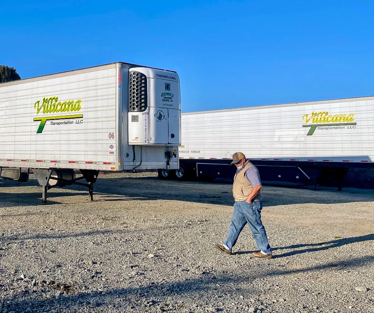 Merardo walking past two Villicana Transportation refrigerated trailers at the Salinas yard